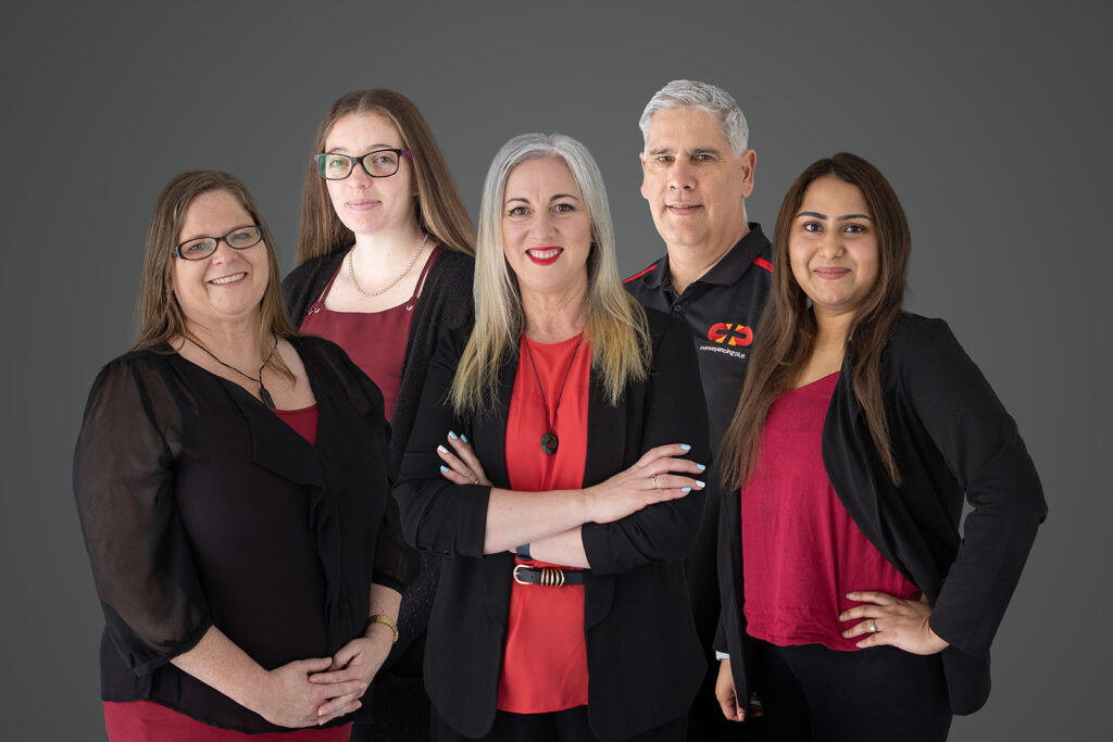 A team photo for Conveyancing Plus Pukekohe of five team members in their branding colours of black and red on a grey background